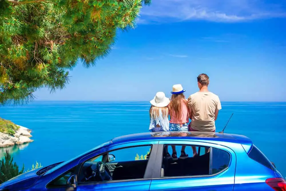 familia sobre coche mira el mar