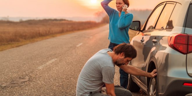 Couple repairing car flat tire on the road