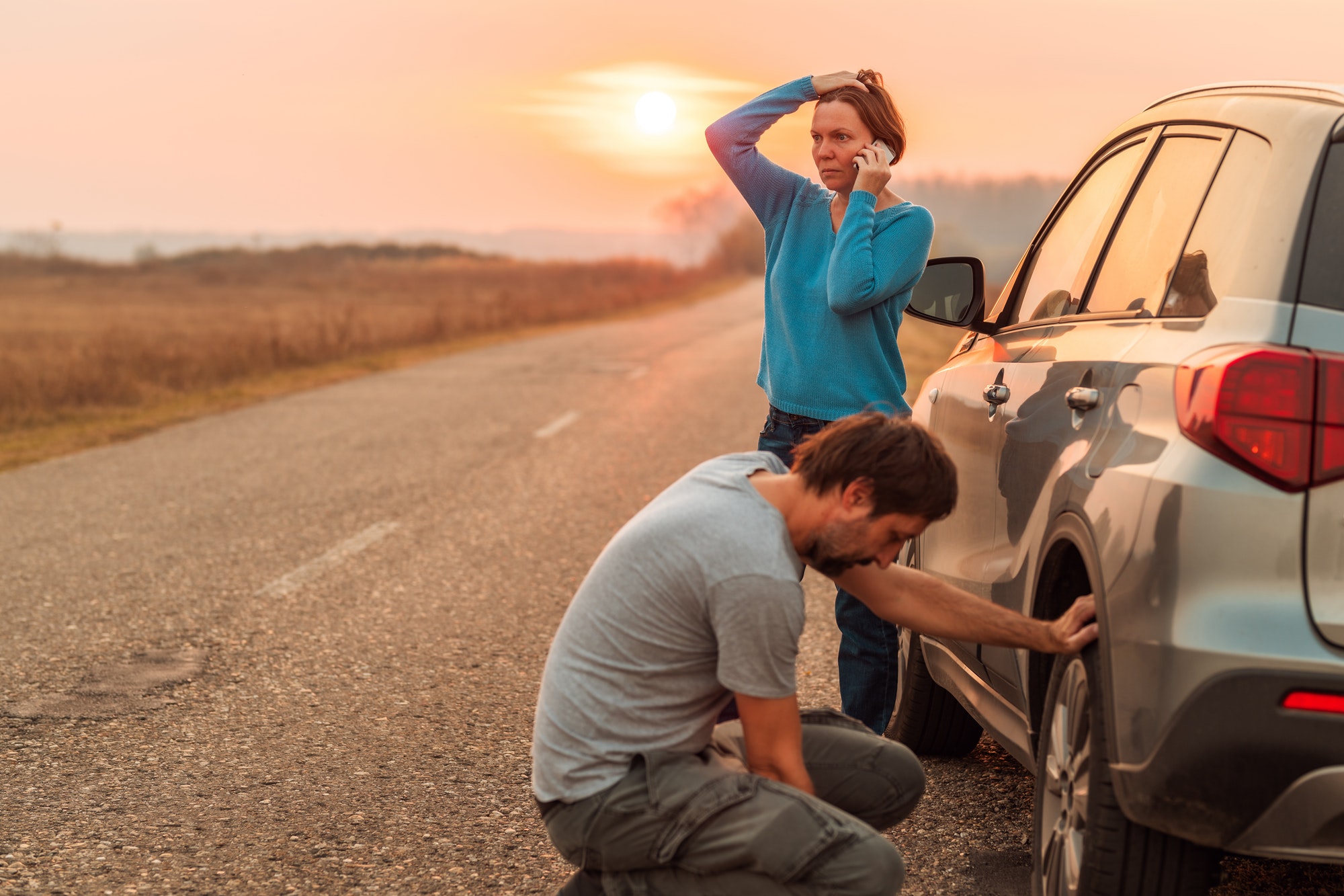 Couple repairing car flat tire on the road