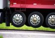 A close-up of the retractable tires referred to as drop axles on a red semi truck trailer viewing