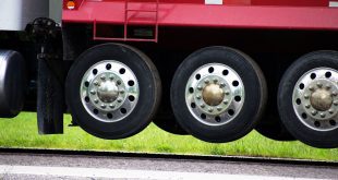 A close-up of the retractable tires referred to as drop axles on a red semi truck trailer viewing