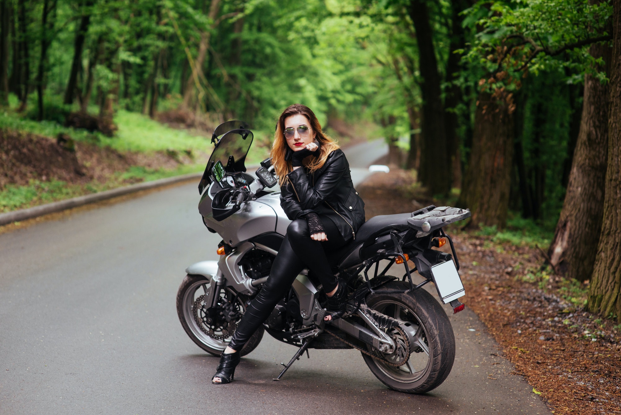 An attractive sexy girl on a sports motorbike posing outside