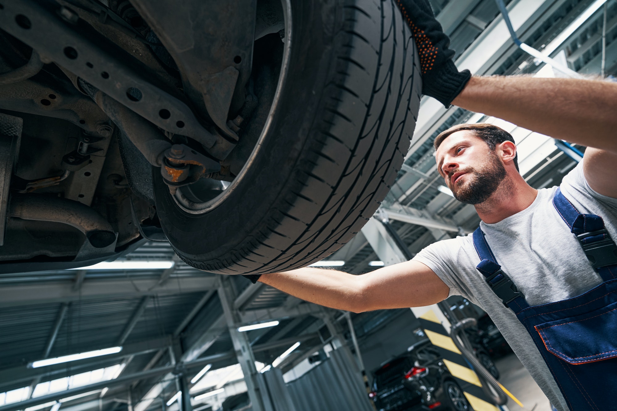 Auto technician detaching a wheel from car