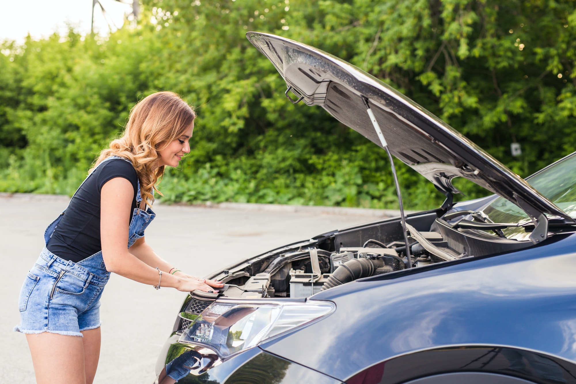 Broken car, accident and people concept - Woman open the car hood and broken automobile on the side