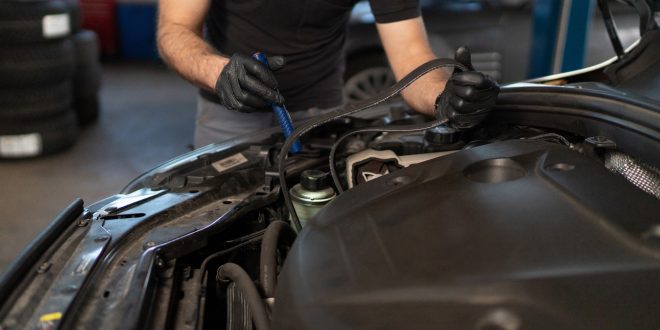 Car service technician changes timing belt of car