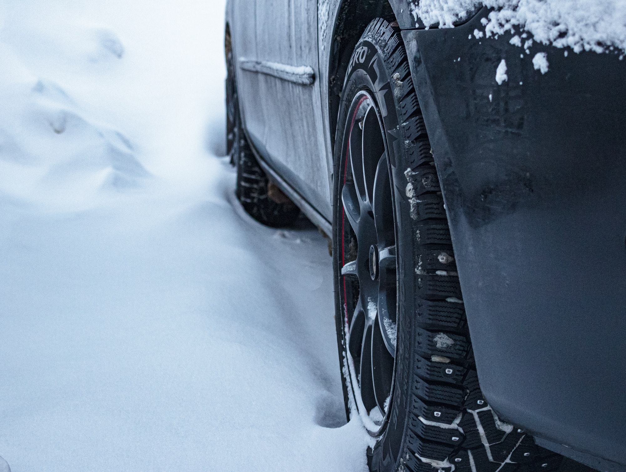 Car with studded winter tyre on the snow parking