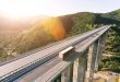 Cargo delivery truck driving on highway bridge on susnet