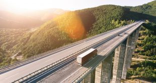 Cargo delivery truck driving on highway bridge on susnet