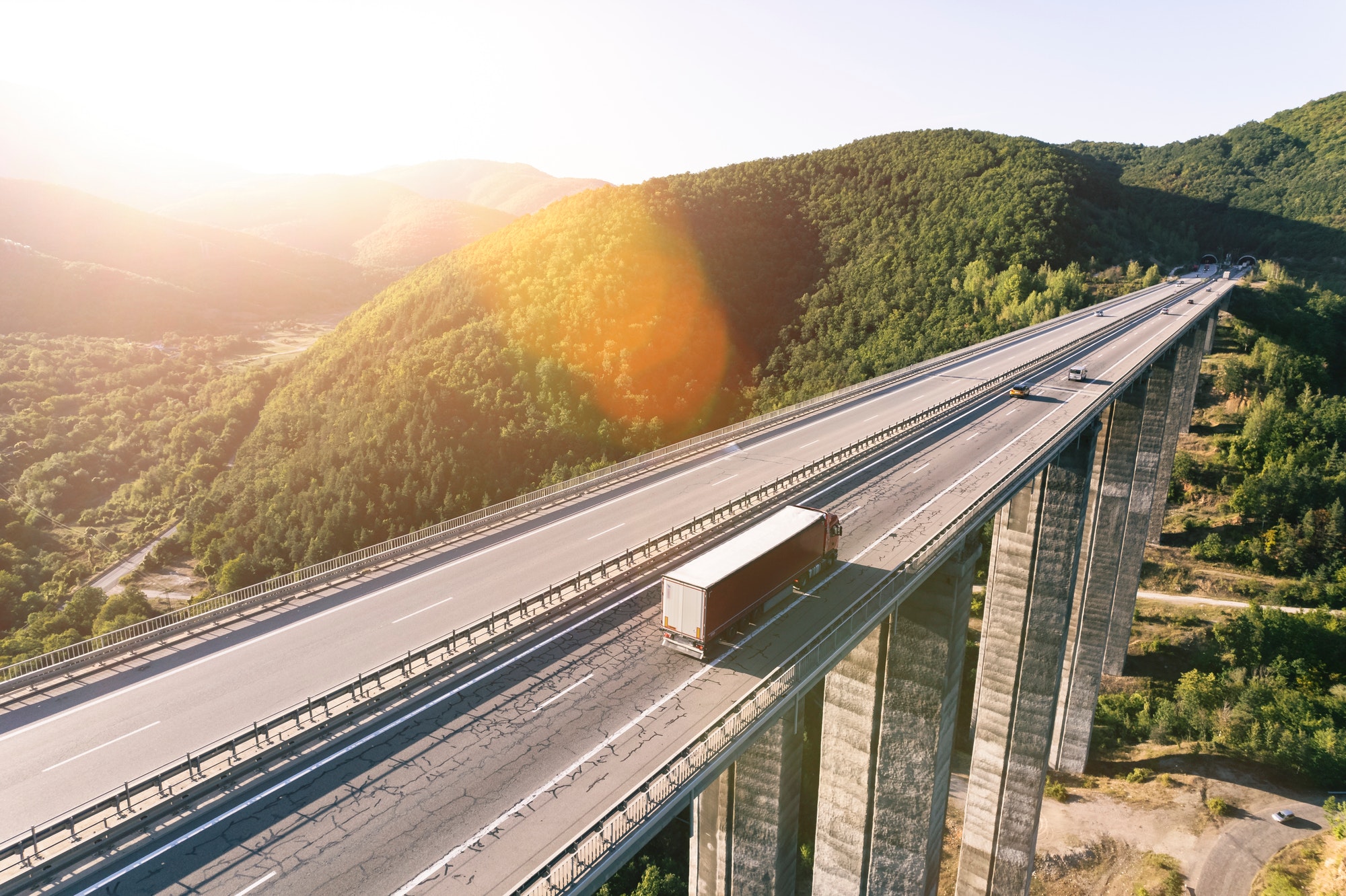 Cargo delivery truck driving on highway bridge on susnet