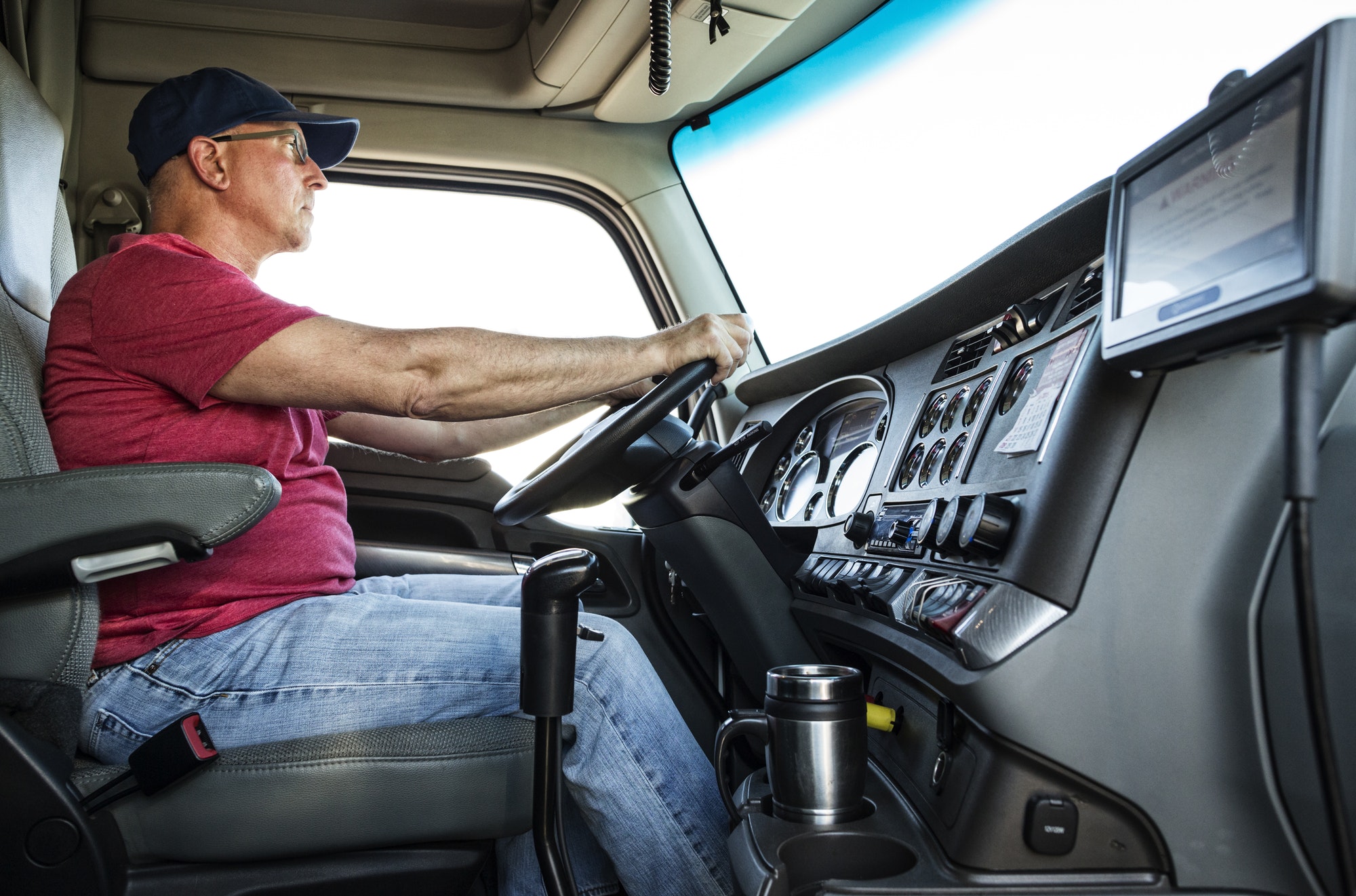 Caucasian man truck driver in the cab of his commercial truck.