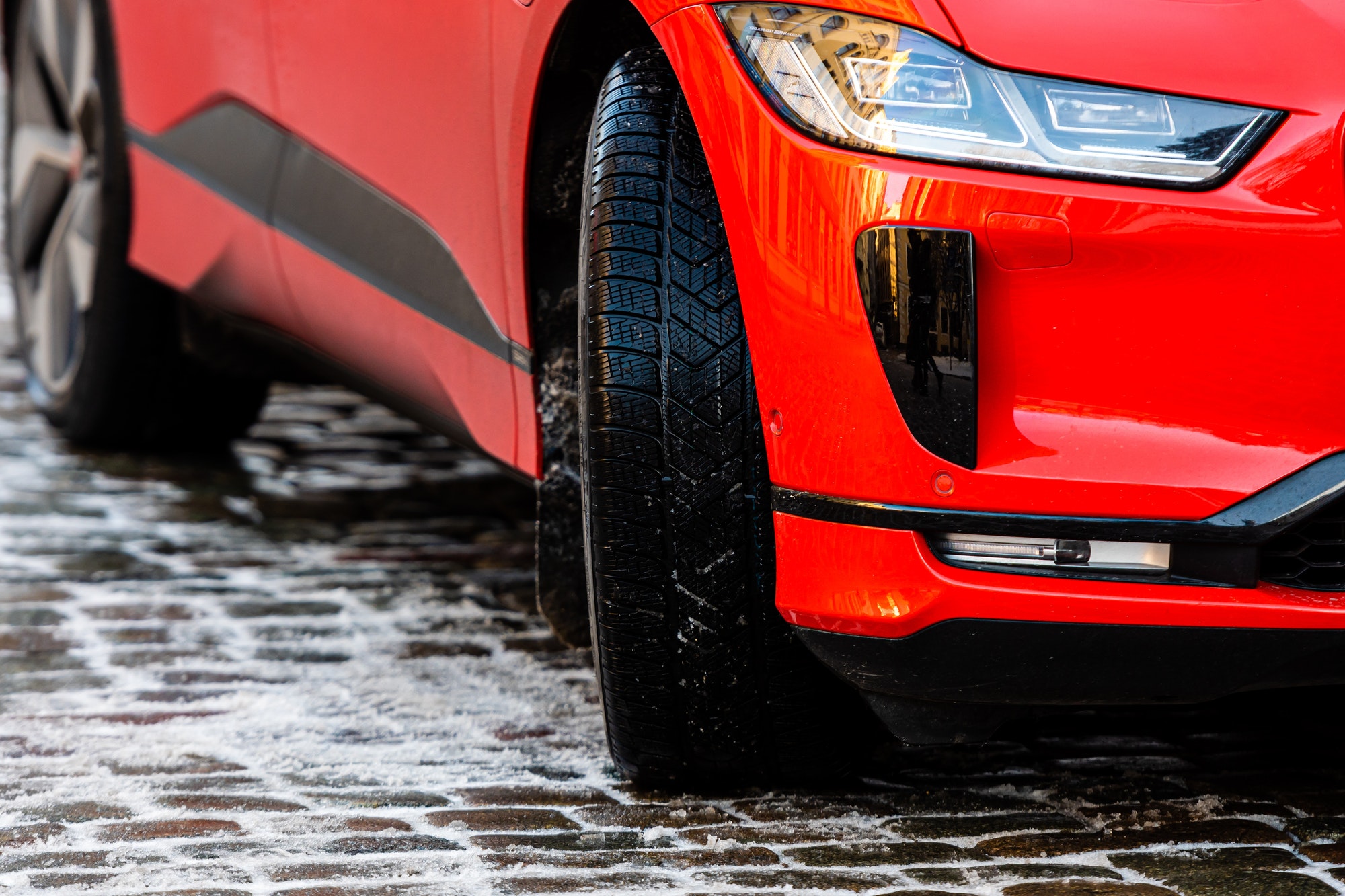Close-up of a red car with winter tires on an icy pavement