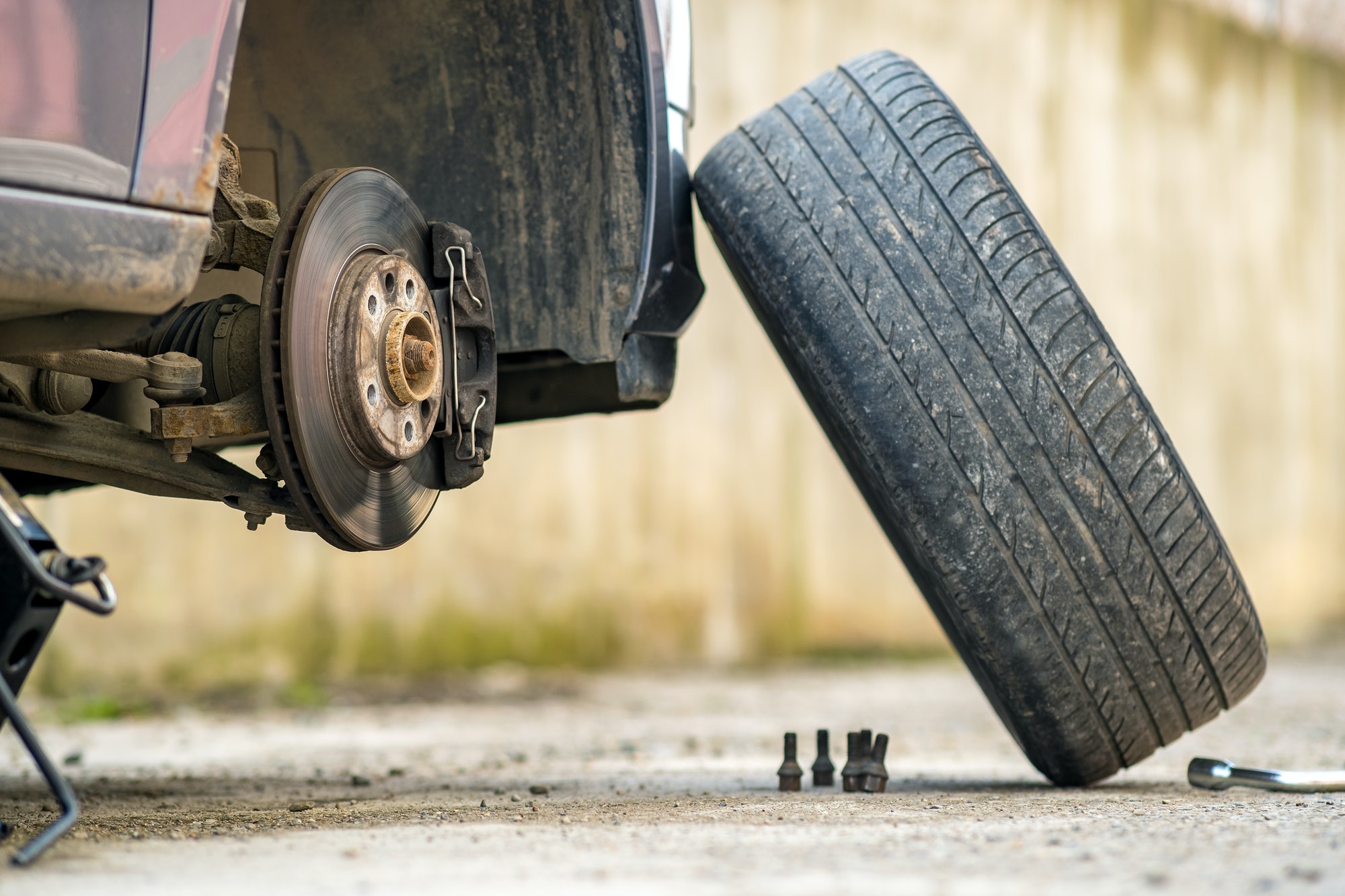 Closeup of a car lifted on jack in process of new wheel tire replacement. Breakdown of a vehicle on