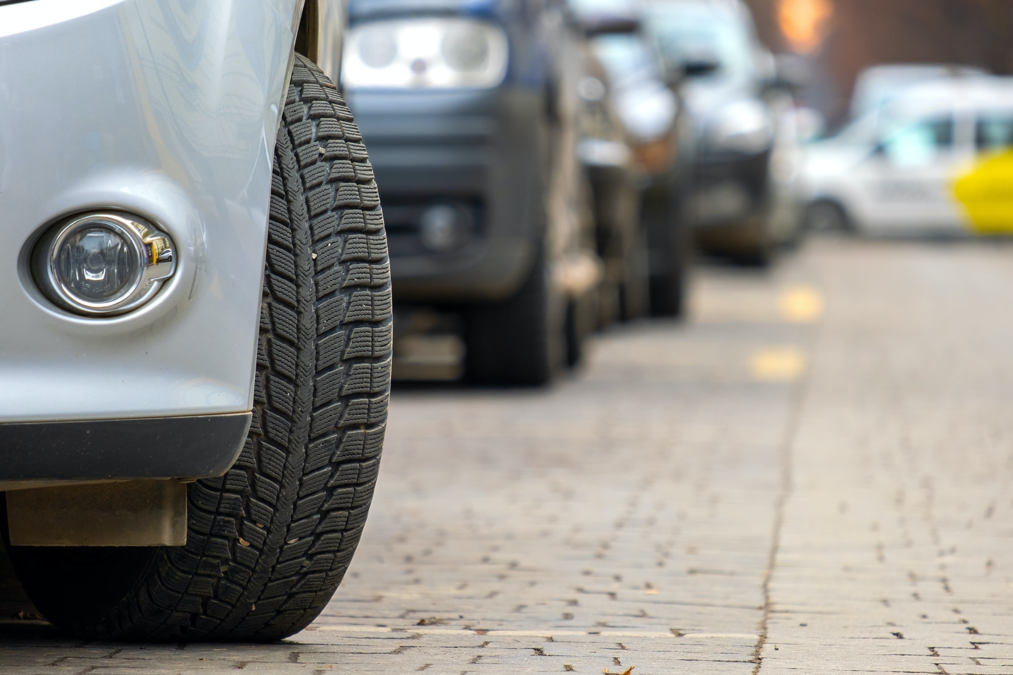 Closeup of parked car on a city street side with new winter rubber tires
