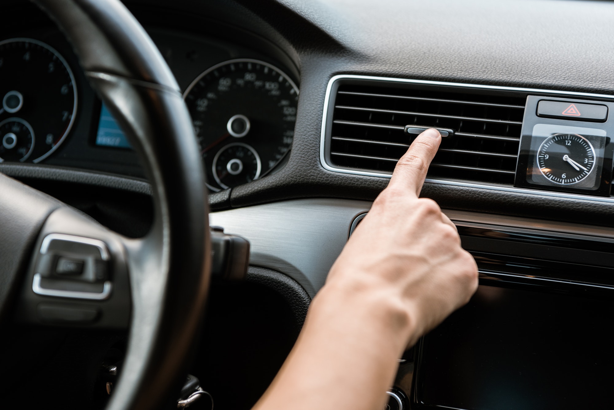 cropped view of woman touching air conditioner switch in car