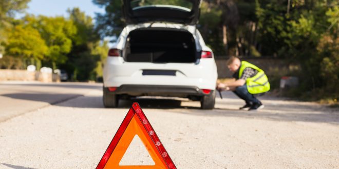 Emergency sign on the background of the car and the man