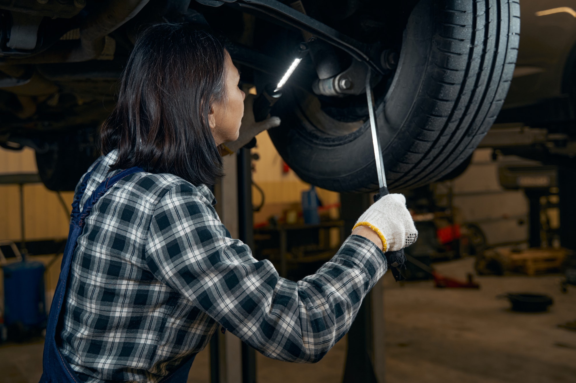 Focused female car technician fixing a tyre