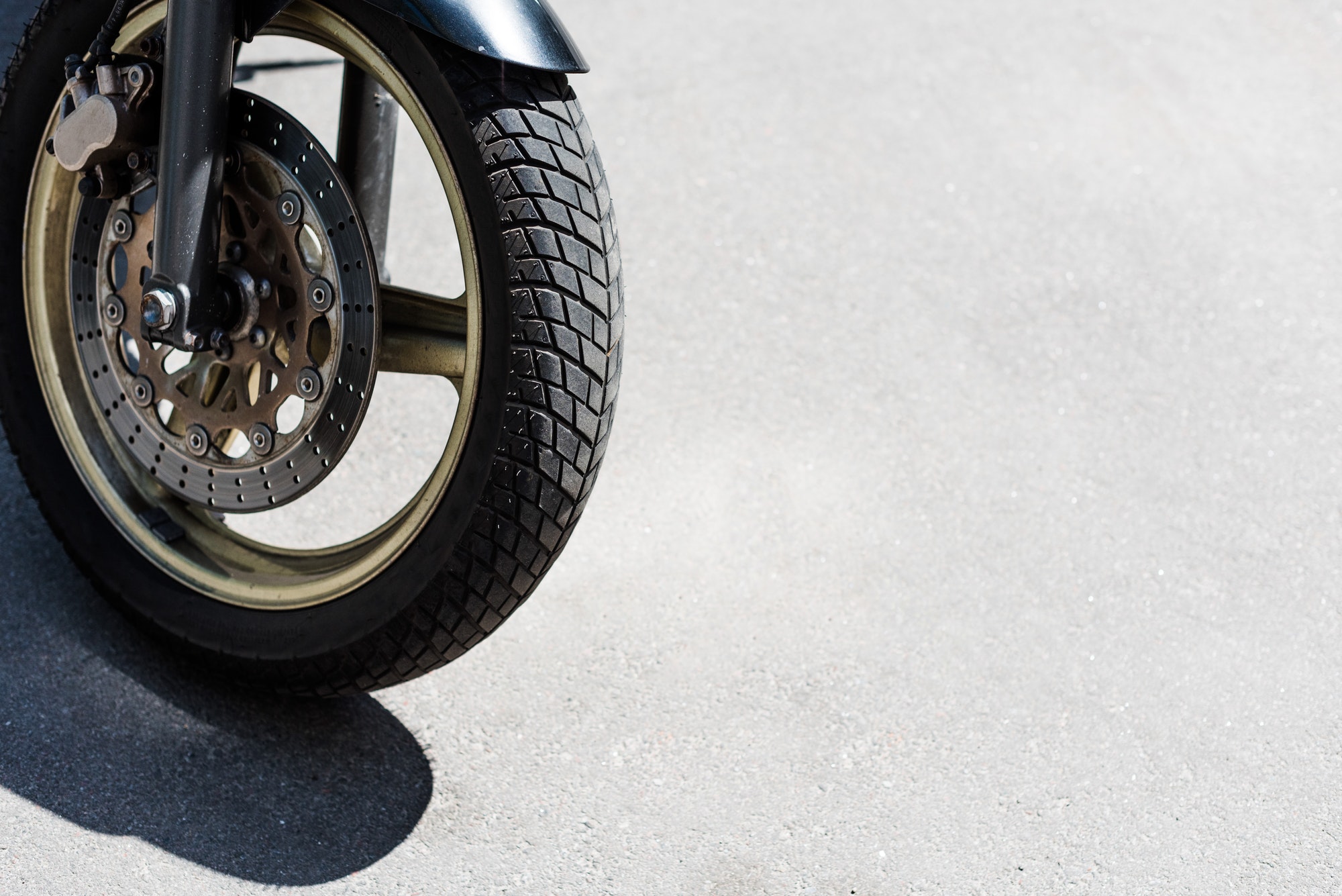Front wheel with black tire of motorcycle on street