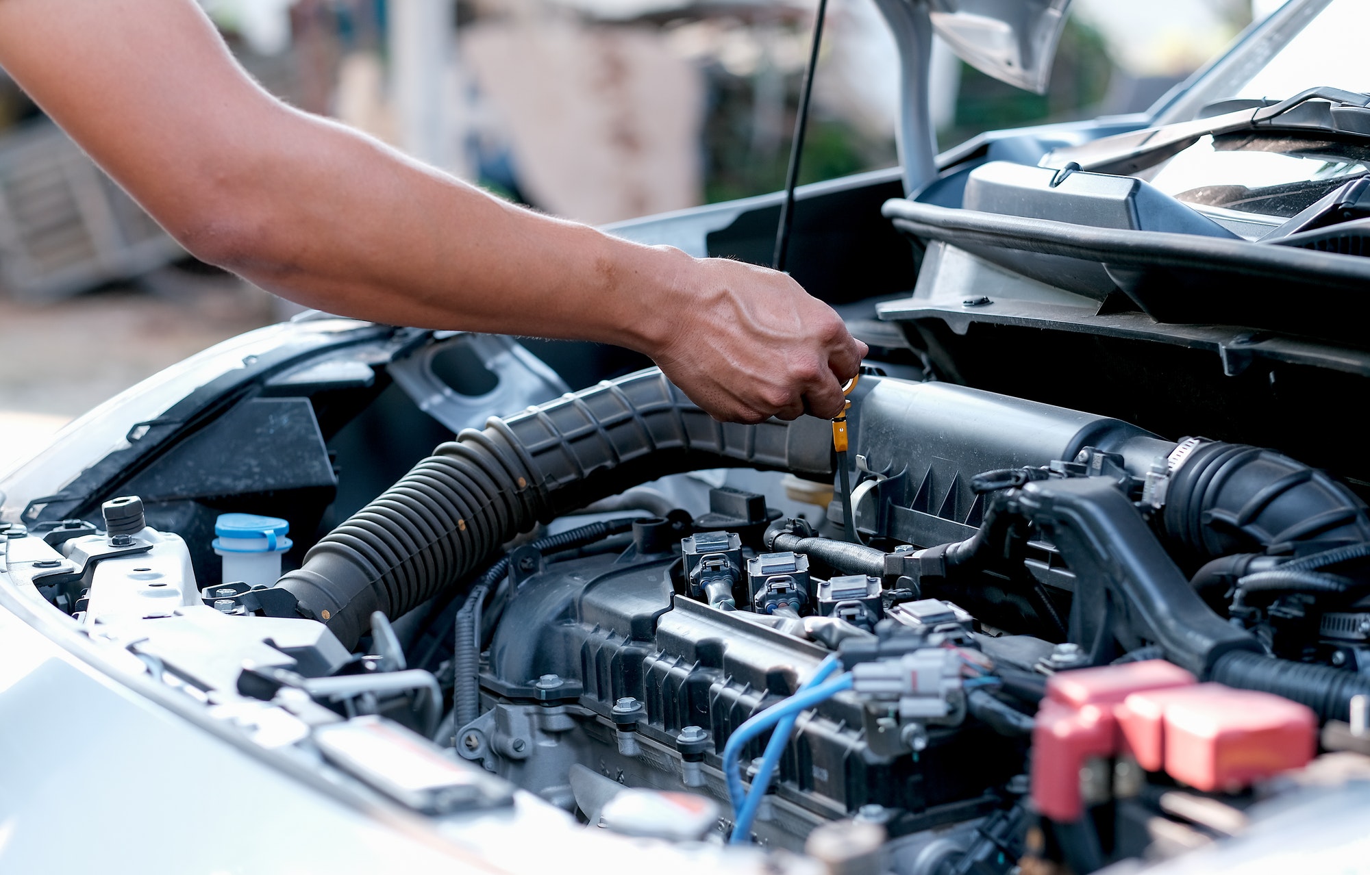 Hands of automotive mechanic check and inspecting the engine of the car.