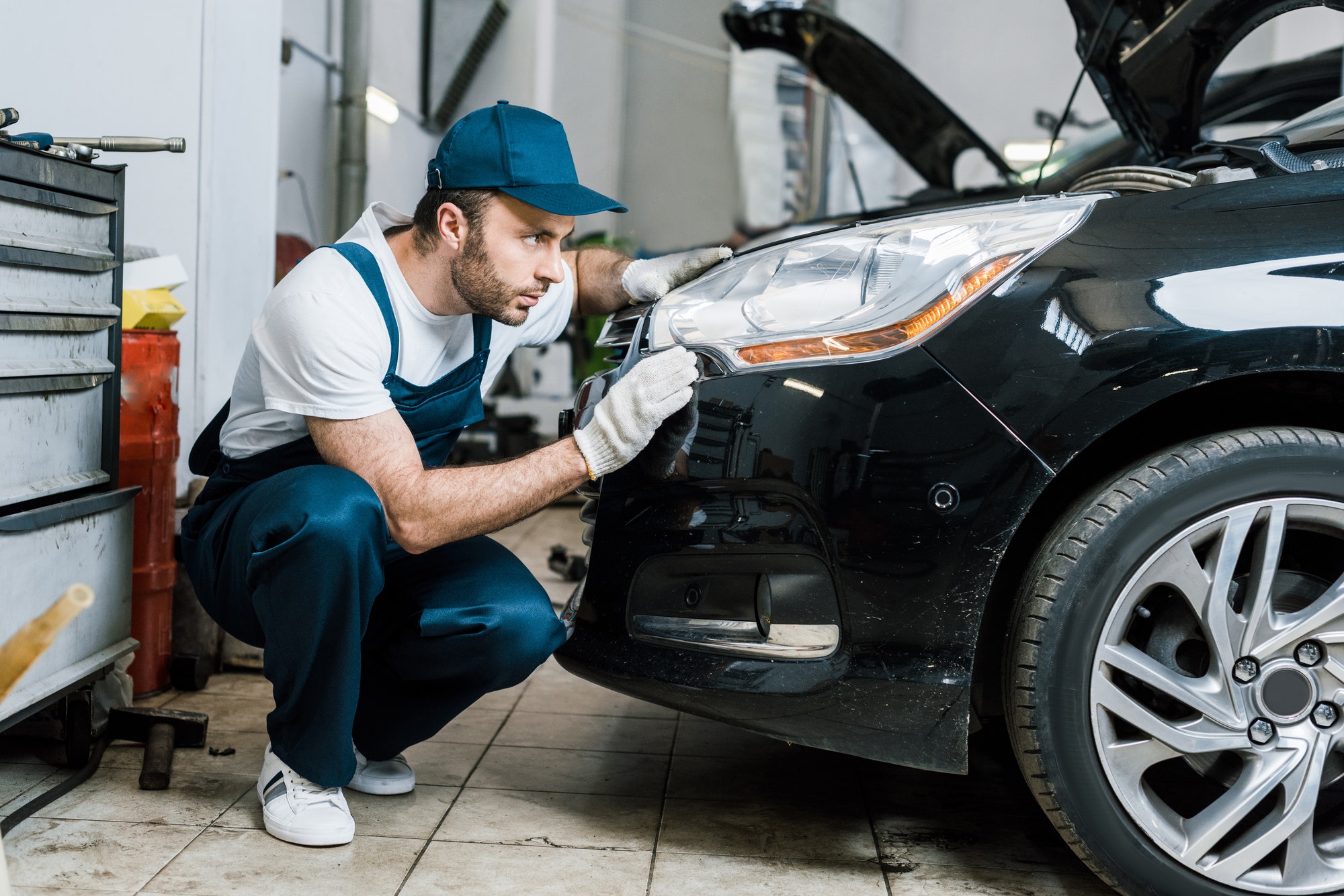 handsome car mechanic looking at tail light in black car