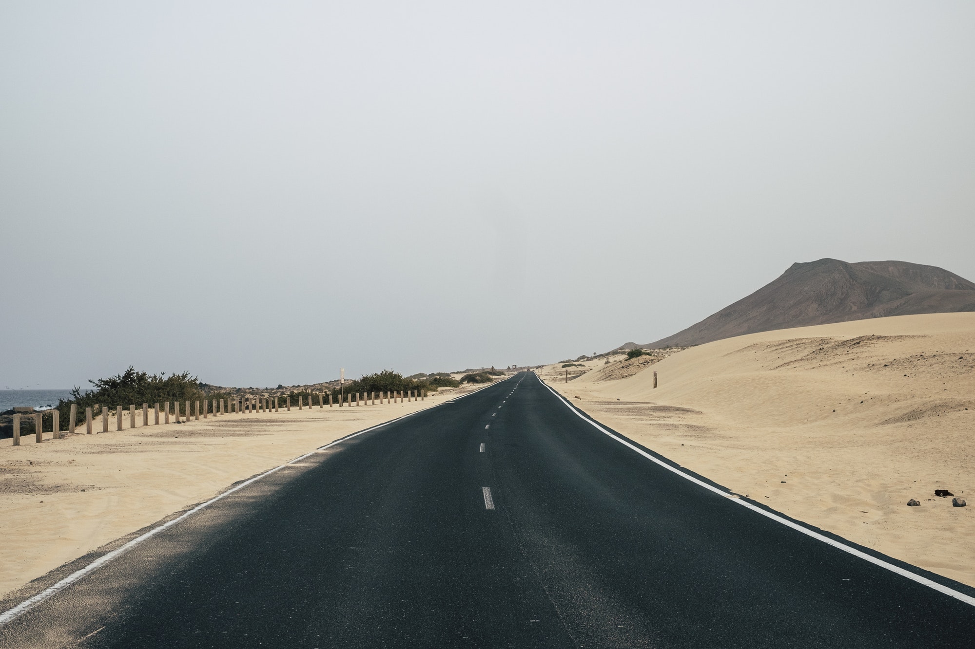 Long asphalt road with sand desert around. Concept of car travel and adventure.