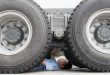 Male factory worker inspecting underneath truck in crane factory, China