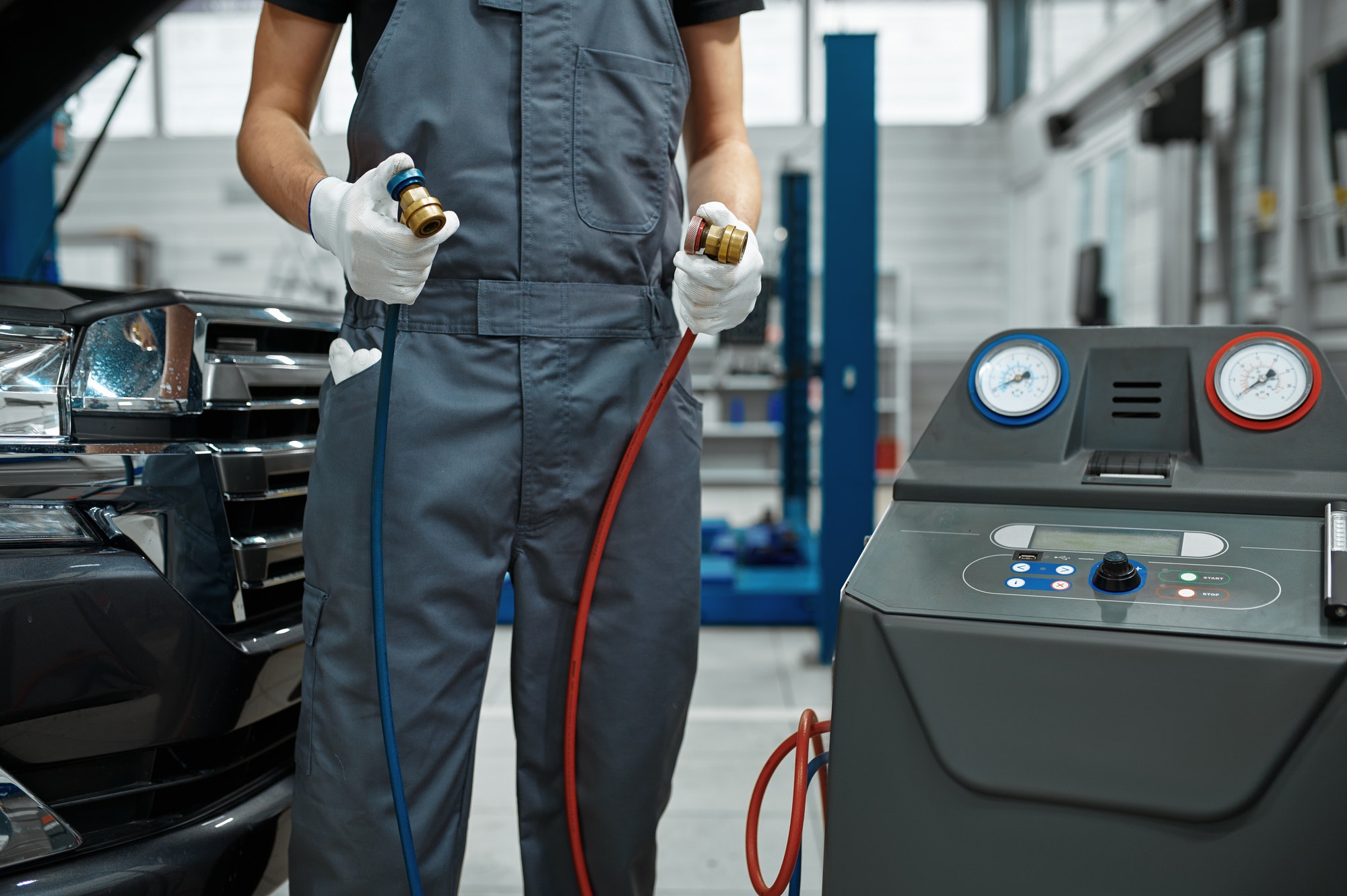 Male mechanic refills air conditioner, car service