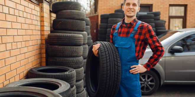 Male worker at the stack of tyres, tire service