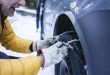 Man putting the snow chains on his car