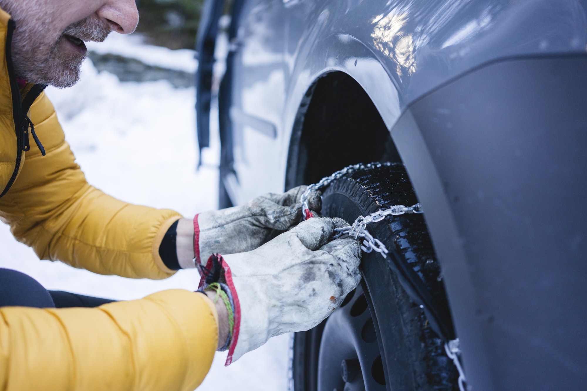 Man putting the snow chains on his car