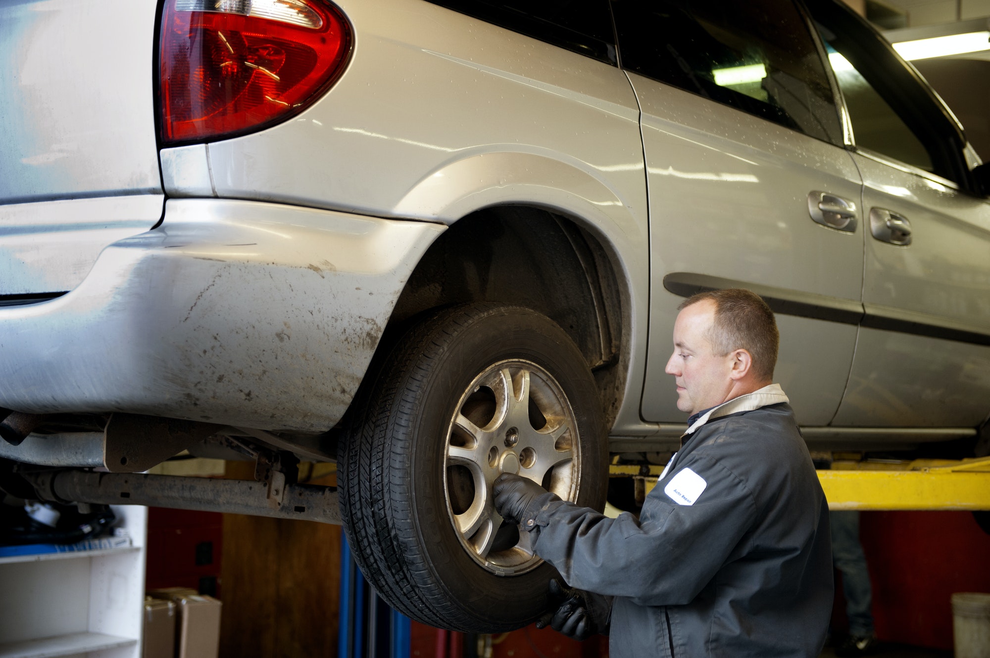 Mechanic Examining Car Tire At Auto Repair Shop