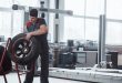 Mechanic holding a tire at the repair garage. Replacement of winter and summer tires