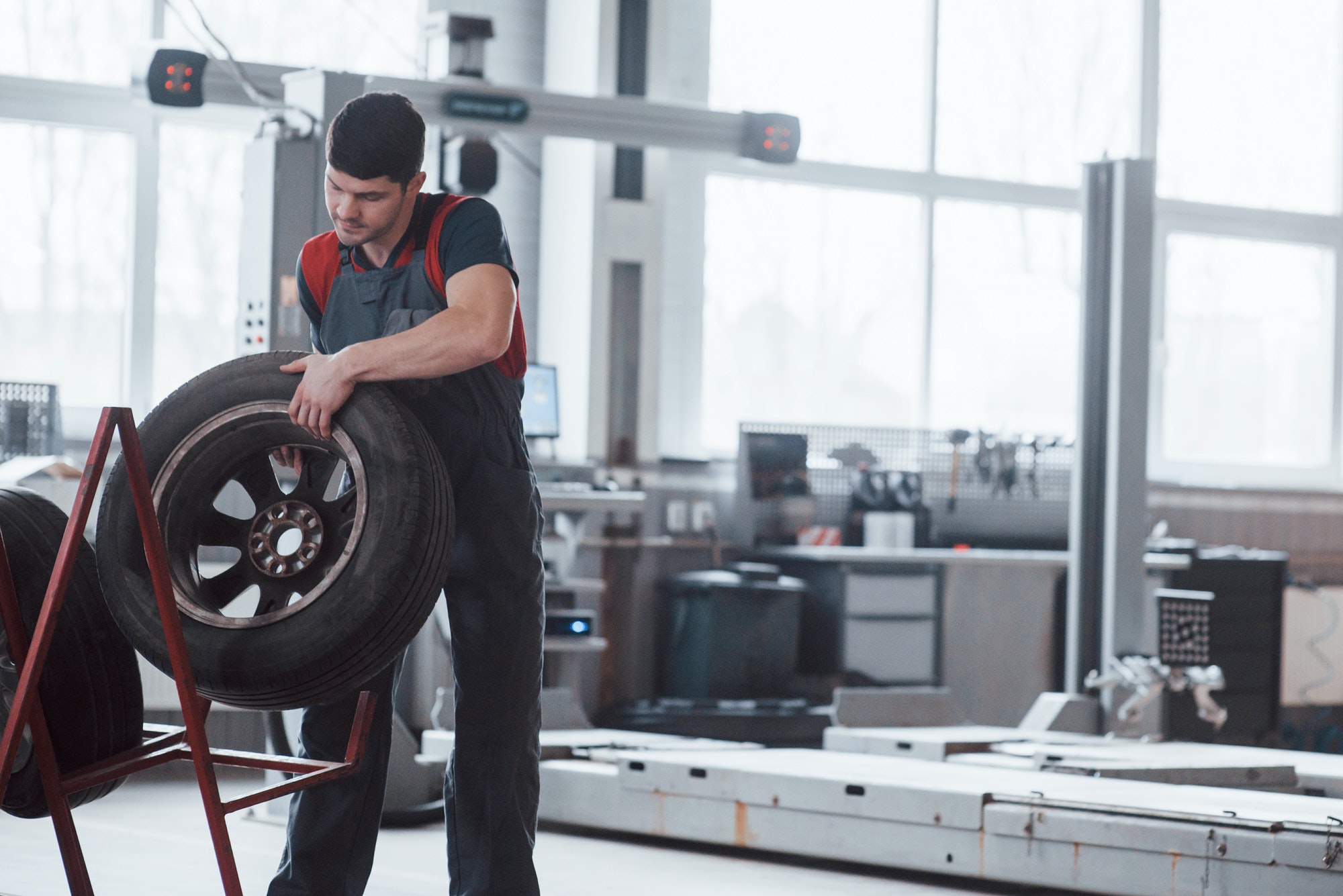 Mechanic holding a tire at the repair garage. Replacement of winter and summer tires