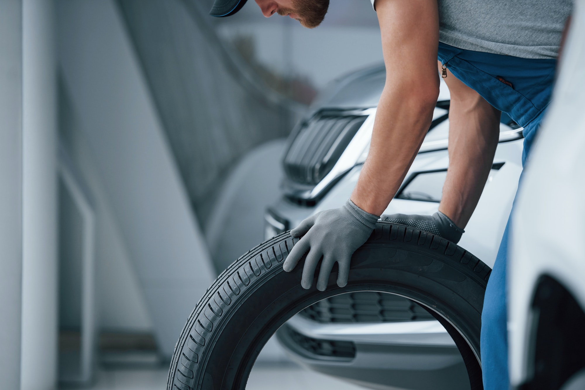Mechanic holding a tire at the repair garage. Replacement of winter and summer tires