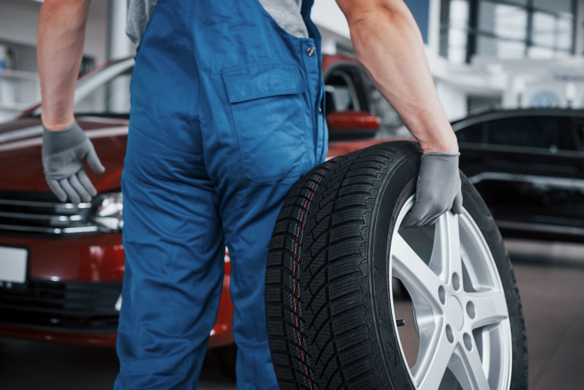 Mechanic holding a tire tire at the repair garage. replacement of winter and summer tires