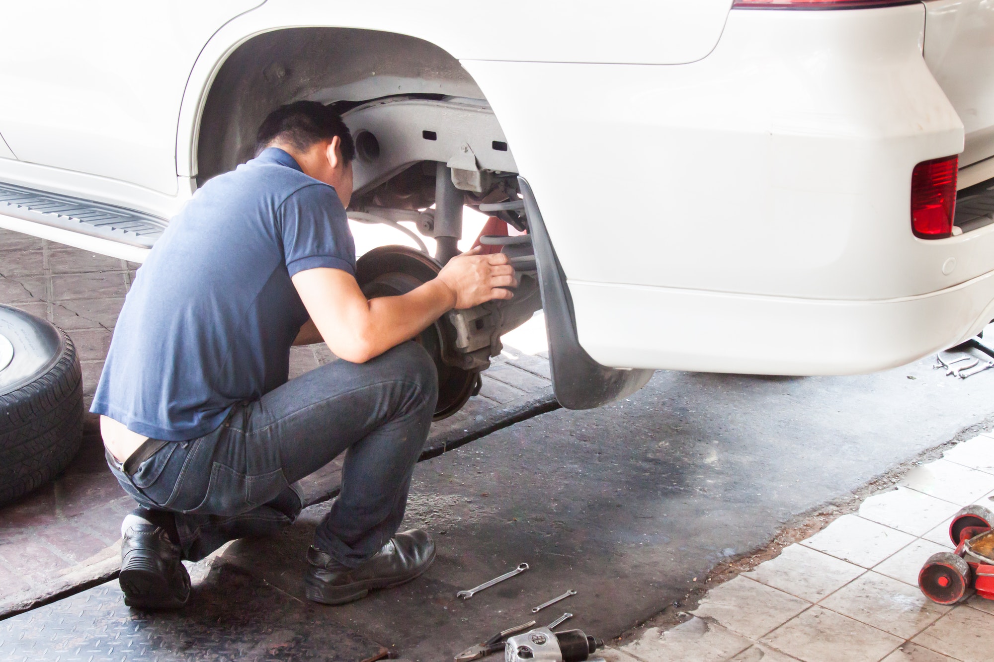 Mechanic inspecting the suspension and brakes of car at workshop