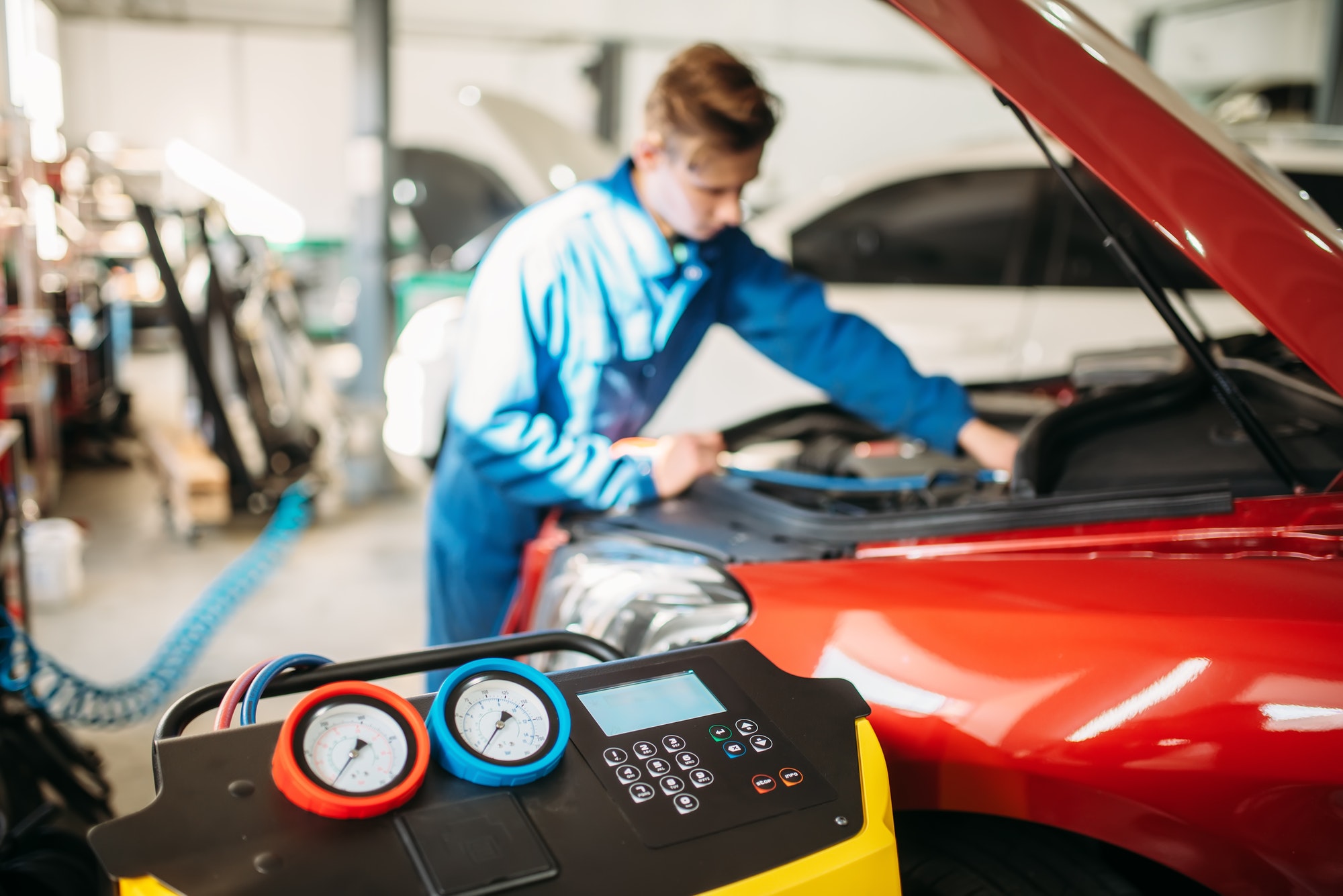 Mechanic pumps freon into the conditioning system