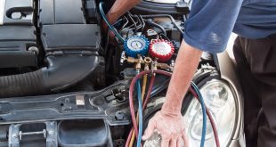 Mechanic with manometer inspecting auto vehicle air-condition co
