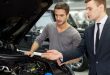 Power engine. Handsome young salesman showing all the car features to the customer