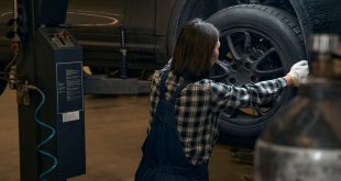 Qualified female mechanic replacing a tyre on a car