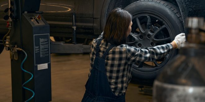 Qualified female mechanic replacing a tyre on a car