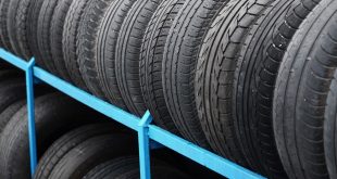 Rack with variety of car tires in automobile store. Many black tires. Tire stack background