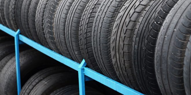 Rack with variety of car tires in automobile store. Many black tires. Tire stack background