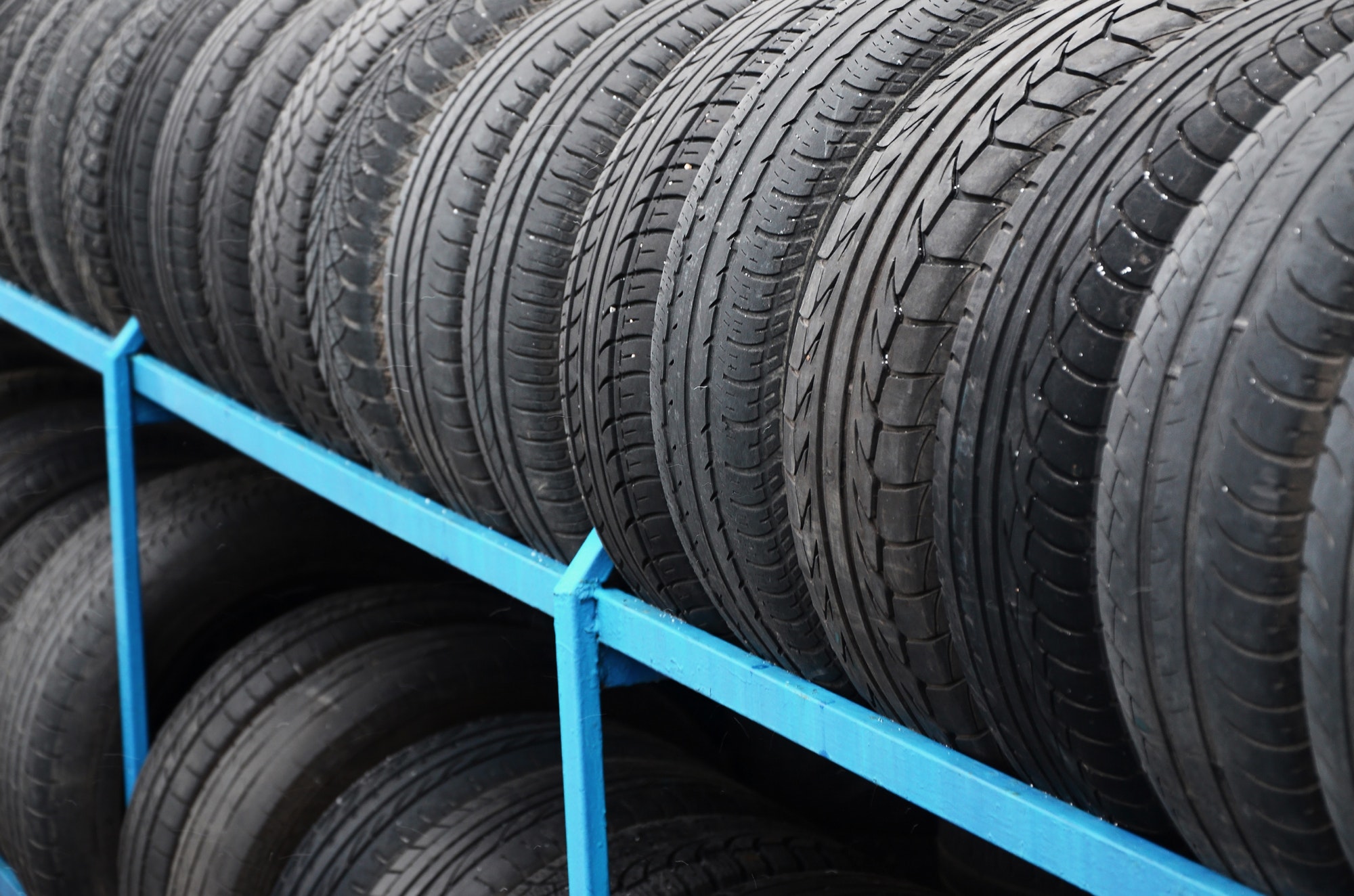 Rack with variety of car tires in automobile store. Many black tires. Tire stack background