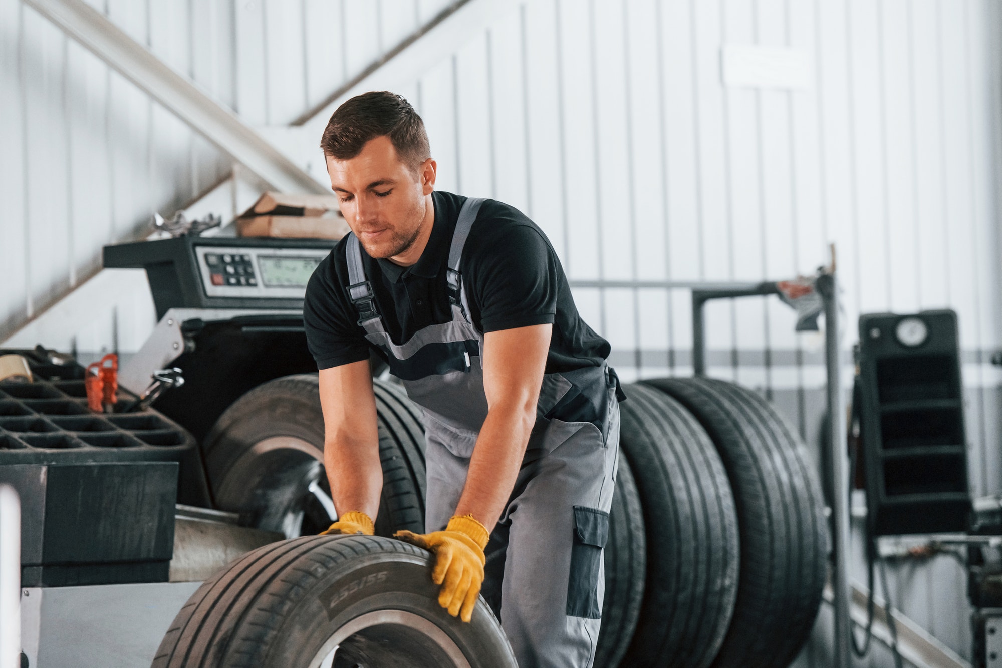 Replacement of the old tire. Man in uniform is working in the auto service