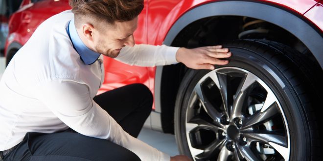 Salesman checking the shiny rims in new car