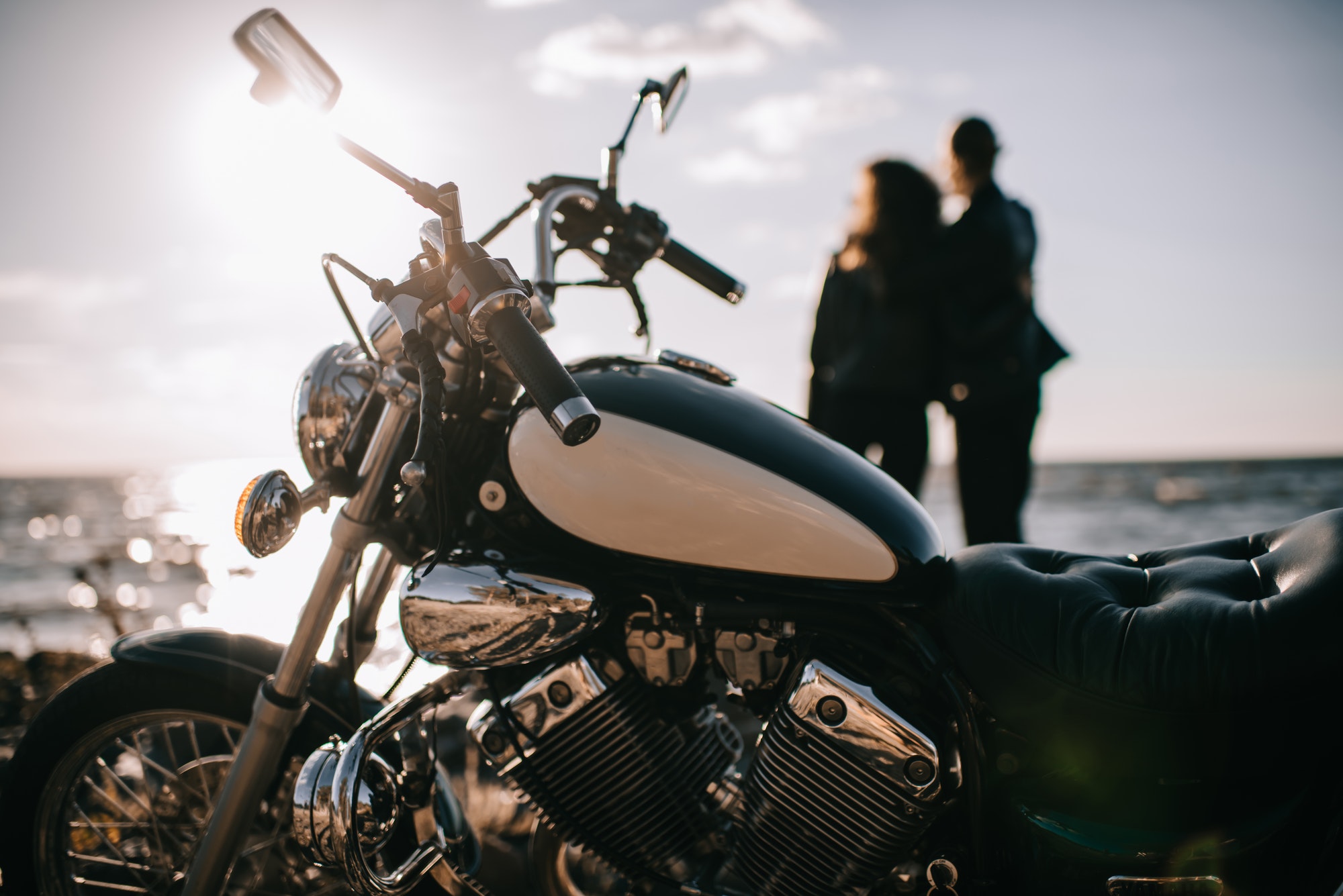 selective focus of classical chopper motorbike and couple looking at sea on background