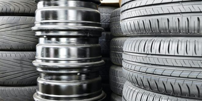 Stack of car tyres and wheel rims in an auto repair shop garage.