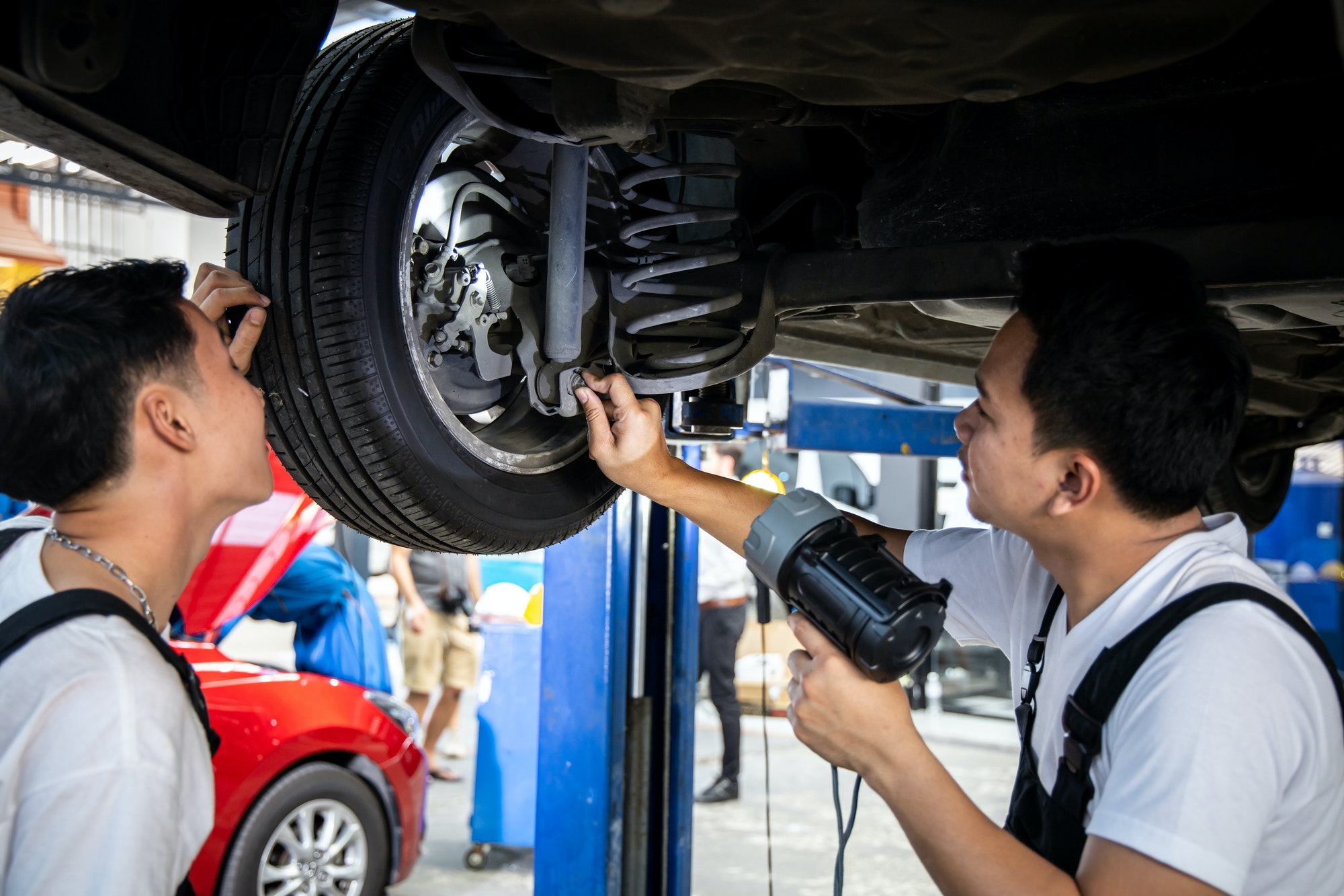 Two mechanic was checking the car suspension.