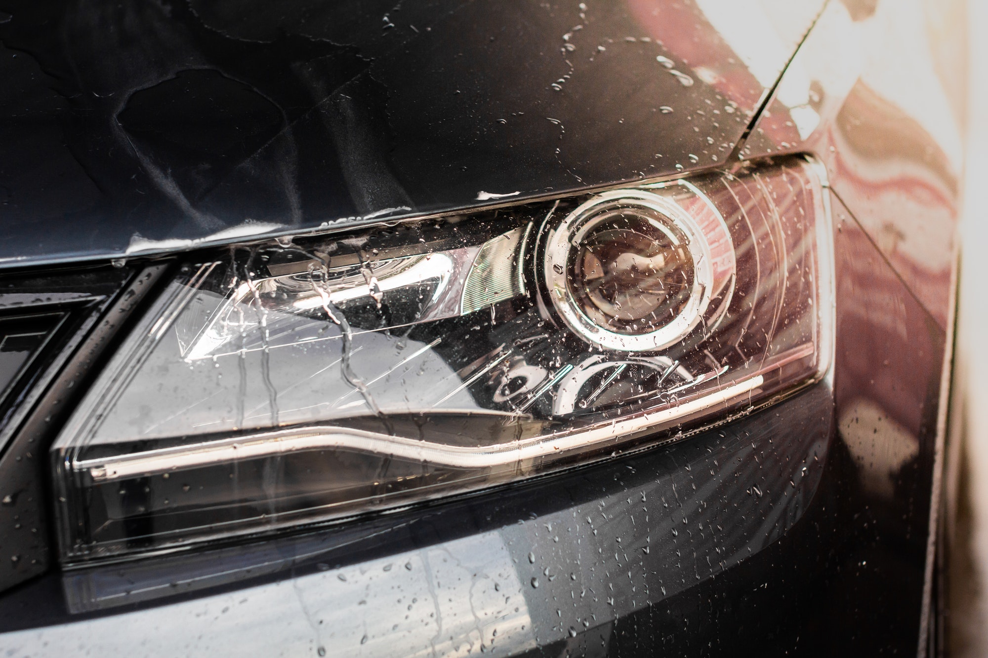 Water drops and foam on the car light in the vehcle wash station. Cleaning automobile concept