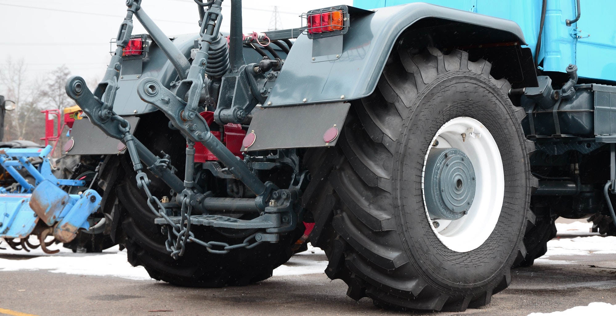 Wheels of back view of new tractor in snowy weather. Agricultural vehicle back